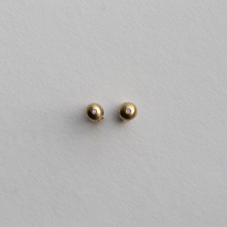 front view of 18ct yellow gold stud earrings highlighting the curved silhouette and satin surface with diamonds