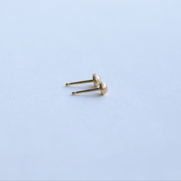 Side view of 18ct yellow gold stud earrings highlighting the curved silhouette and satin surface with diamonds