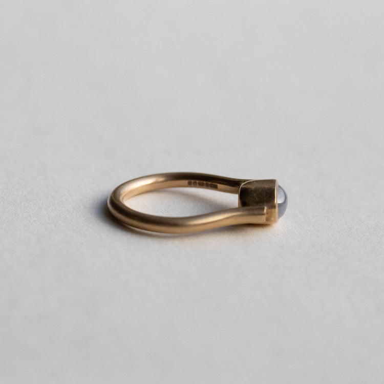 Modern 9ct yellow gold pillar ring with a single bezel-set grey cabochon star sapphire, photographed as flat side view