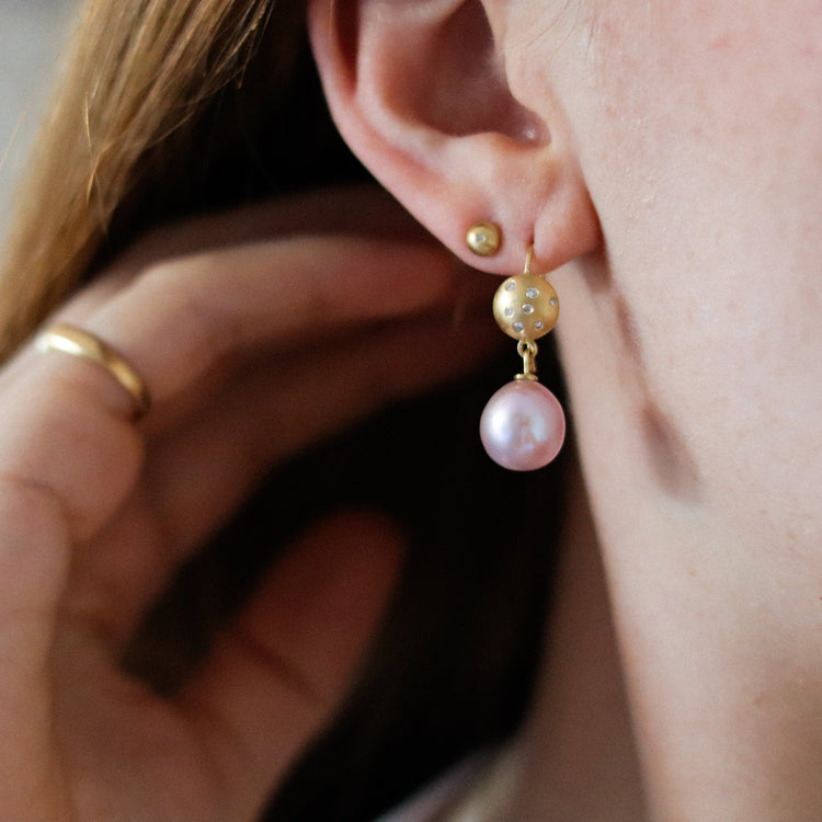 Luxury 18ct yellow gold drop earring with diamond-set sphere and blush pink pearl, worn on the ear.