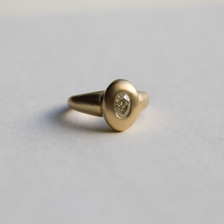 solid heavy 18ct yellow gold curved oval signet ring with oval natural yellow diamond with brushed gold. photographed on paper front view