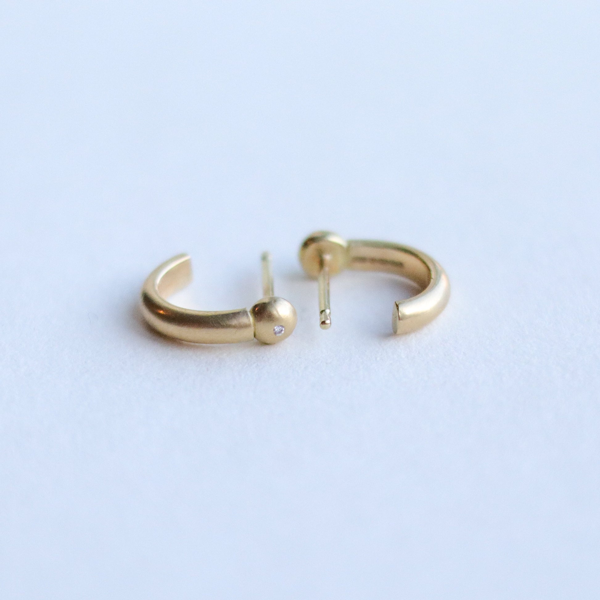 Detail shot of 18ct yellow gold diamond set sculptural gold hoop earrings highlighting smooth curves and warm gold tone