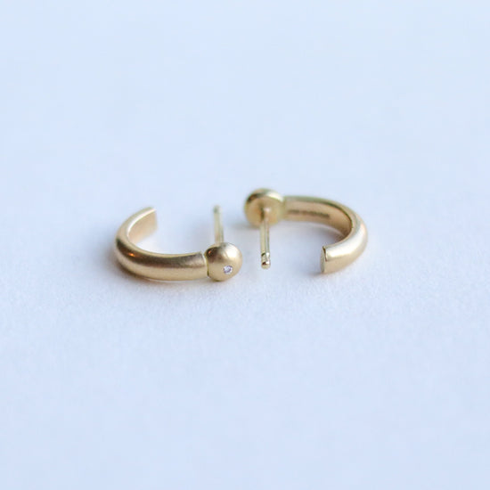 Detail shot of 18ct yellow gold diamond set sculptural gold hoop earrings highlighting smooth curves and warm gold tone