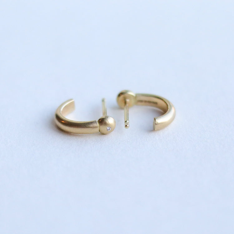 Detail shot of 18ct yellow gold diamond set sculptural gold hoop earrings highlighting smooth curves and warm gold tone