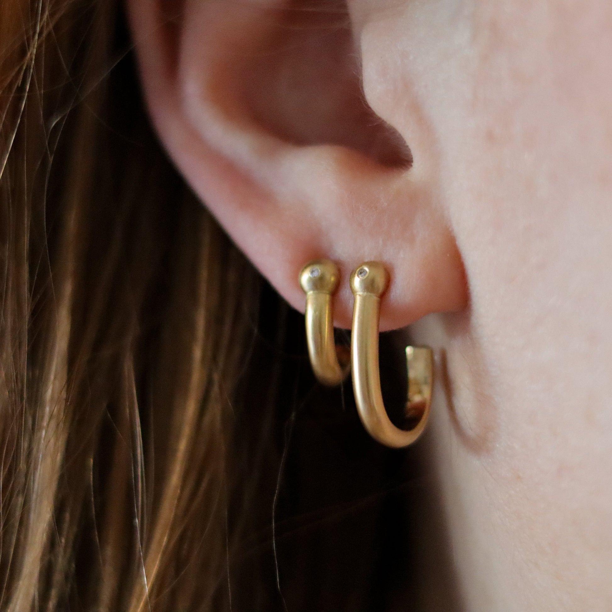 Goldfinch Jewellery. Minimalist 18k diamond set yellow gold hoop earrings with a brushed finish, photographed as a set on model