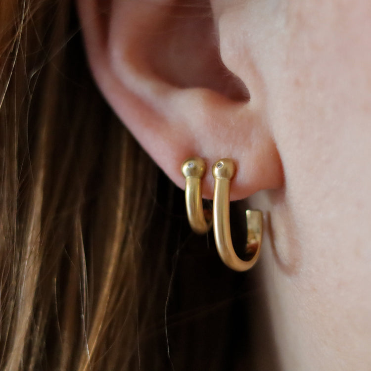 Goldfinch Jewellery. Minimalist 18k diamond set yellow gold hoop earrings with a brushed finish, photographed as a set on model