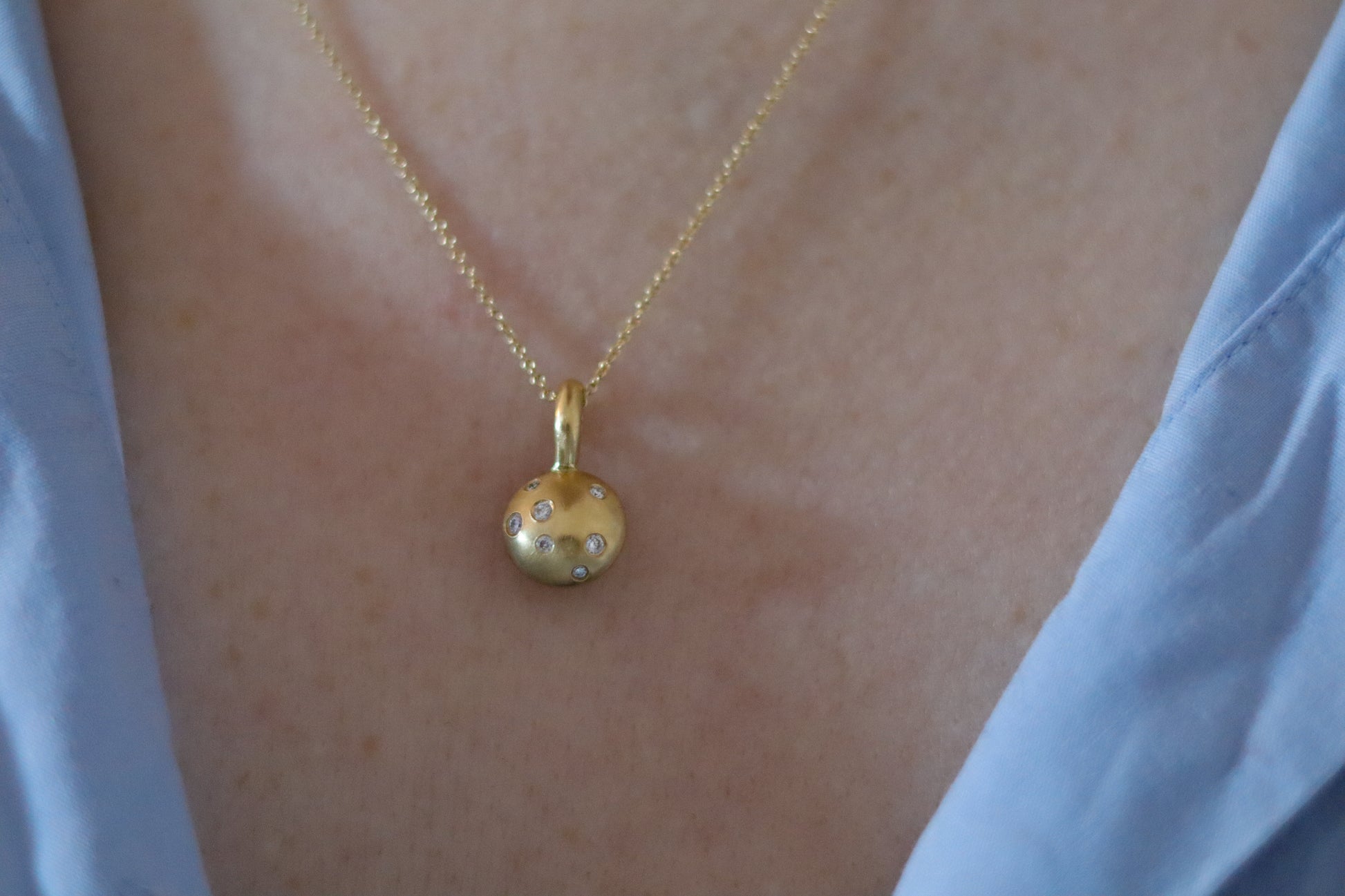 Minimalist solid 18ct yellow gold necklace featuring a brushed gold spherical pendant set with scattered diamonds on a fine solid gold chain worn on model 