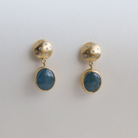 Statement 18ct yellow gold diamond set earrings featuring an oval blue cabochon aquamarine gemstone in a smooth bezel setting, paper shots