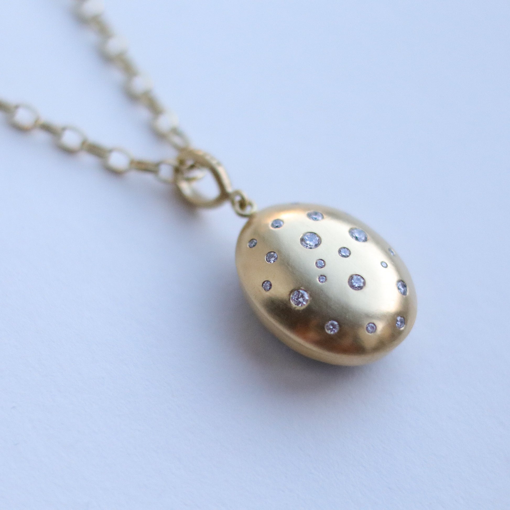 goldfinch jewellery 18ct yellow gold speckled diamond brushed gold egg shaped oval domed pendant on belcher chain close up paper shot