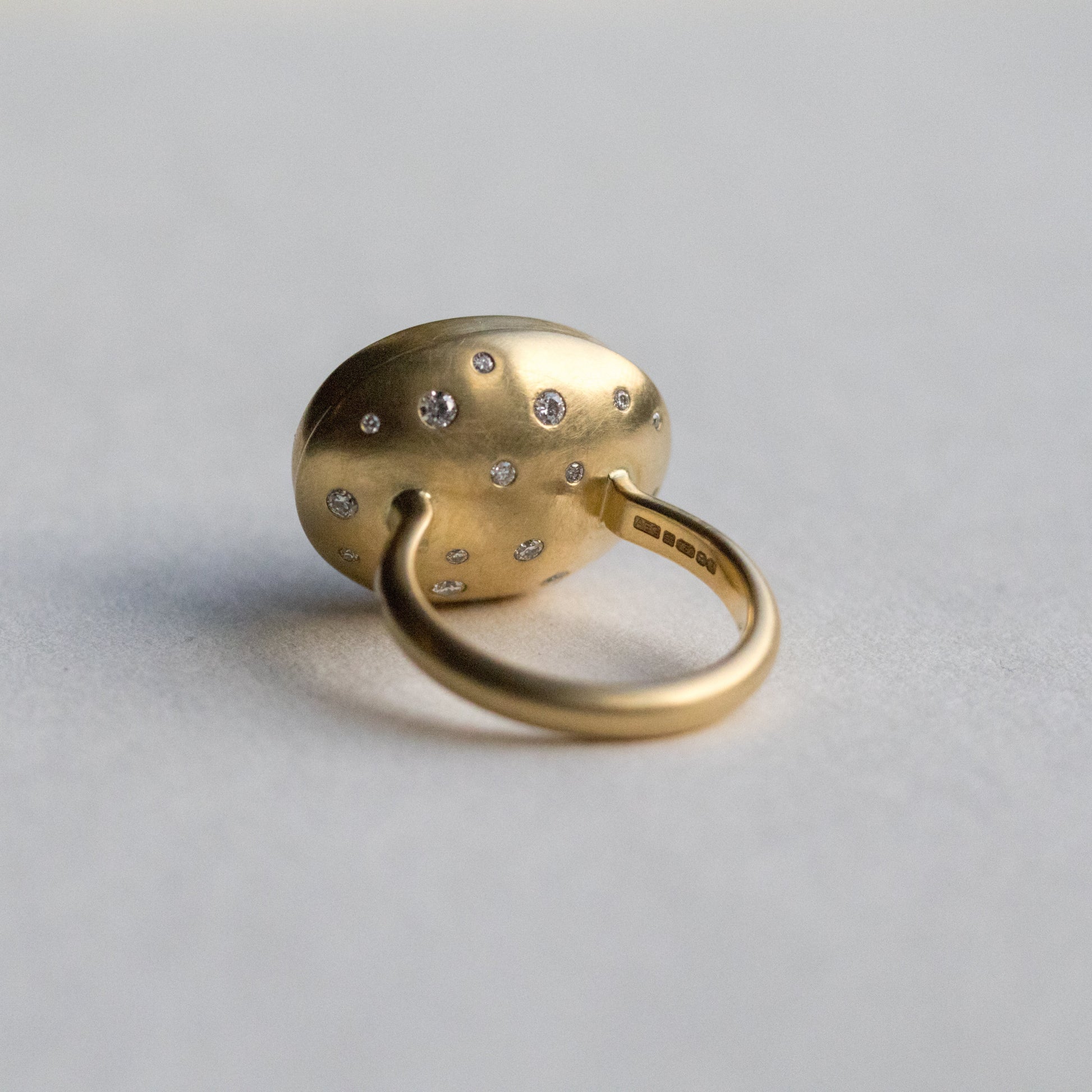 Angled view of an 18ct yellow gold ring, highlighting diamond accents on the band and underneath the setting
