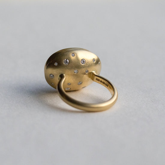 Angled view of an 18ct yellow gold ring, highlighting diamond accents on the band and underneath the setting