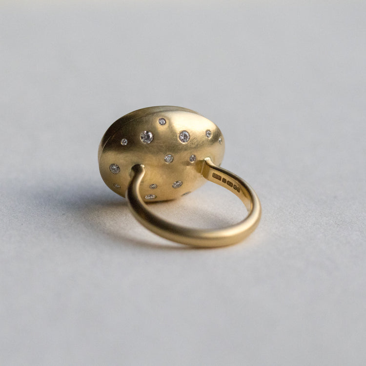 Angled view of an 18ct yellow gold ring, highlighting diamond accents on the band and underneath the setting