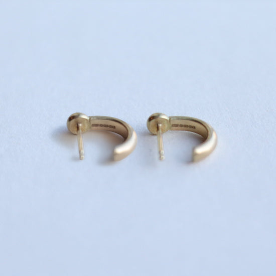 Back view of minimalist 18ct yellow gold hoop earrings with post fastening, styled on a clean white background.