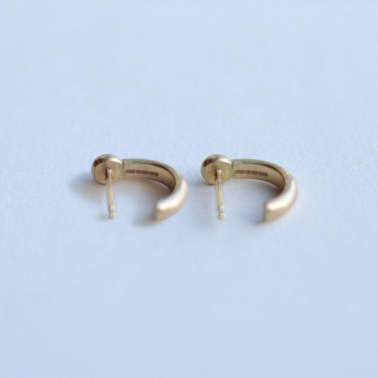 Back view of minimalist 18ct yellow gold hoop earrings with post fastening, styled on a clean white background.