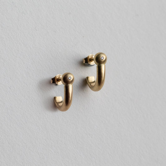 Side profile of modern 18ct yellow gold hoop earrings with diamond set rounded ball detail, photographed in soft natural light.
