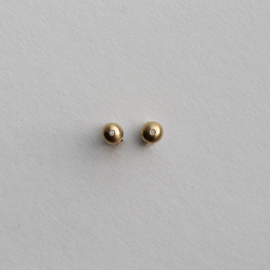 front view of 18ct yellow gold stud earrings highlighting the curved silhouette and satin surface with diamonds