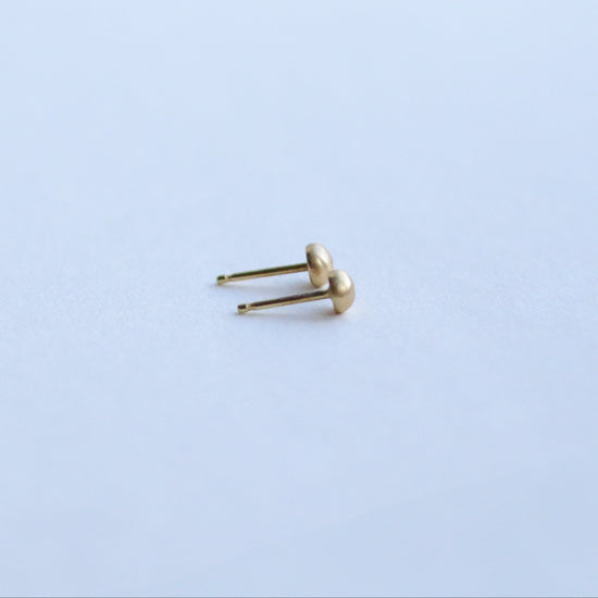 Side view of 18ct yellow gold stud earrings highlighting the curved silhouette and satin surface with diamonds