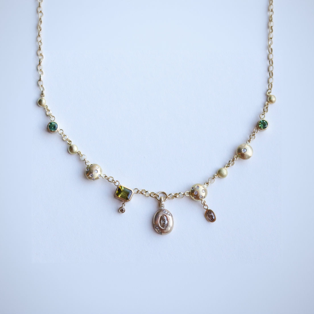 Bespoke cluster necklace in gold with diamonds and gemstones, tourmalines, green, white, brown and champagne tones. bold style.