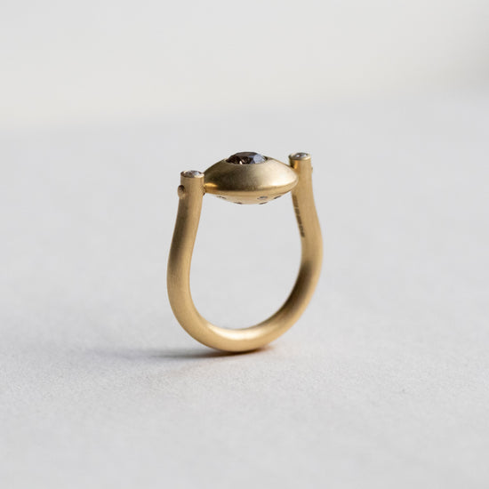 Modern 18ct yellow gold ring with a matte circular spinning disc speckle set with a central natural brown cognac diamond and white side diamonds, paper shot side view