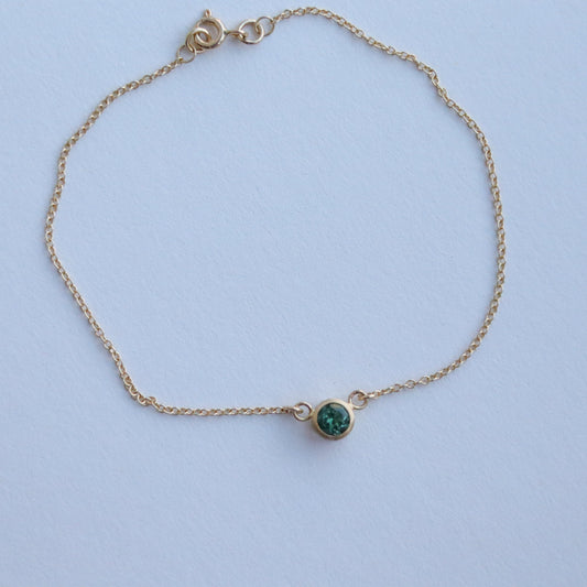 Minimalist brushed 18ct yellow gold necklace featuring a mint green tourmaline on a fine gold chain on paper