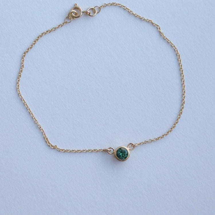 Minimalist brushed 18ct yellow gold necklace featuring a mint green tourmaline on a fine gold chain on paper
