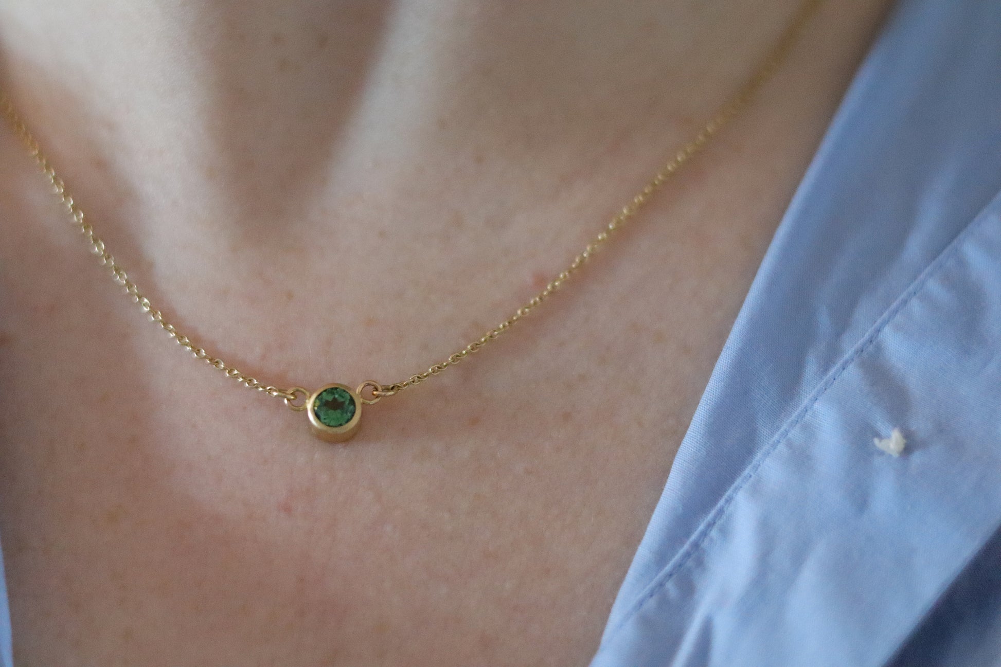 Minimalist brushed 18ct yellow gold necklace featuring a mint green tourmaline on a fine gold chain on model