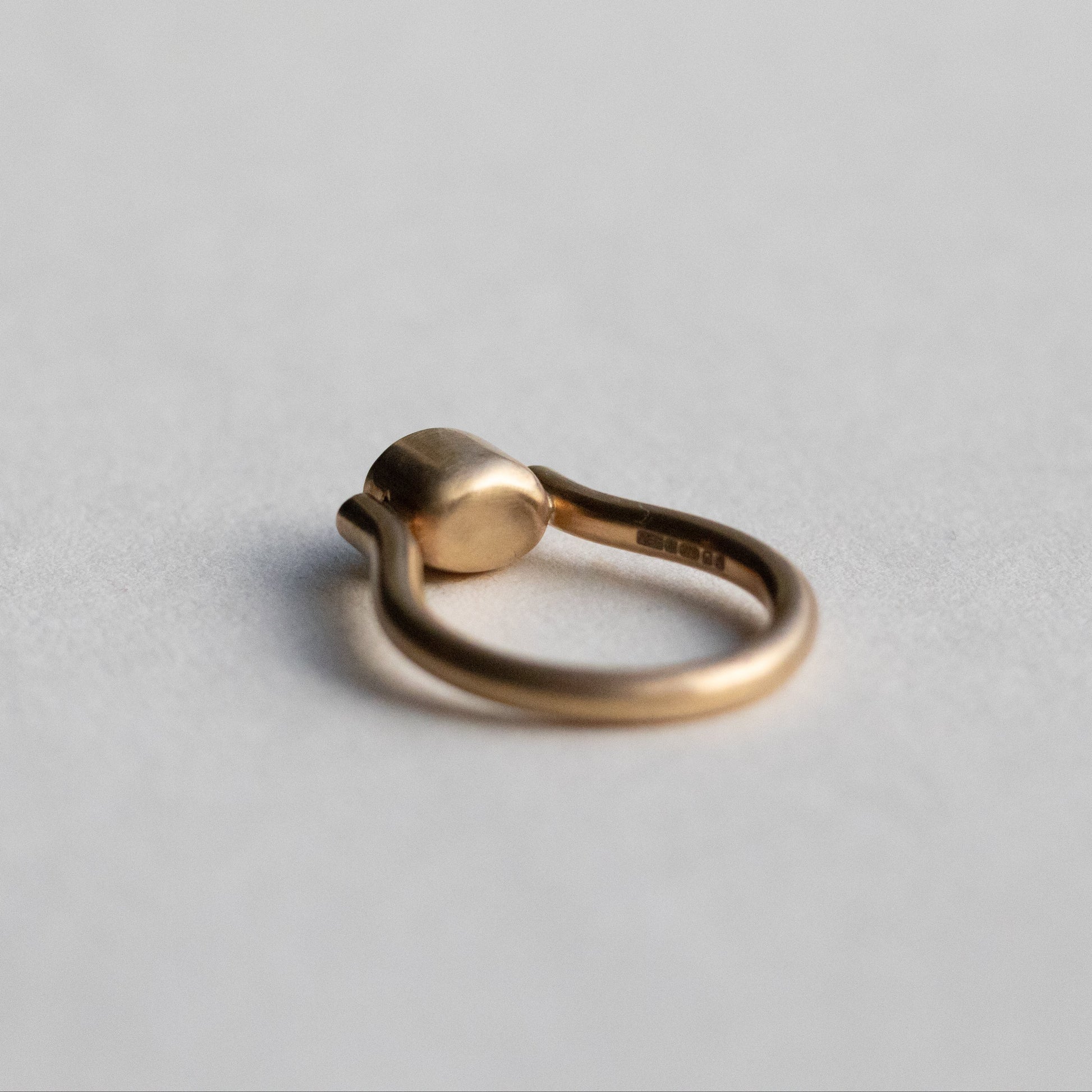 Modern 9ct yellow gold pillar ring with a single bezel-set grey cabochon star sapphire, photographed from inside the ring
