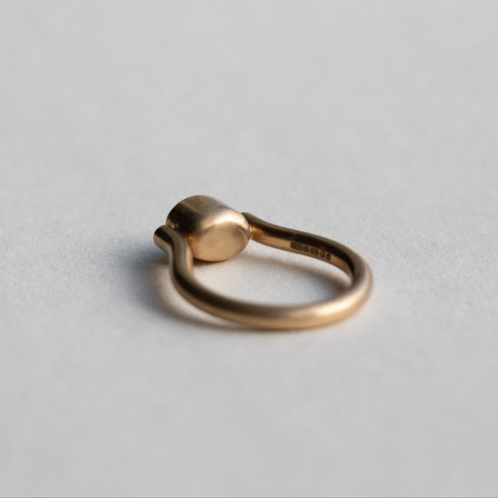 Modern 9ct yellow gold pillar ring with a single bezel-set grey cabochon star sapphire, photographed from inside the ring
