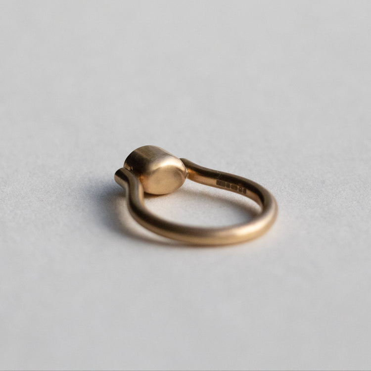 Modern 9ct yellow gold pillar ring with a single bezel-set grey cabochon star sapphire, photographed from inside the ring