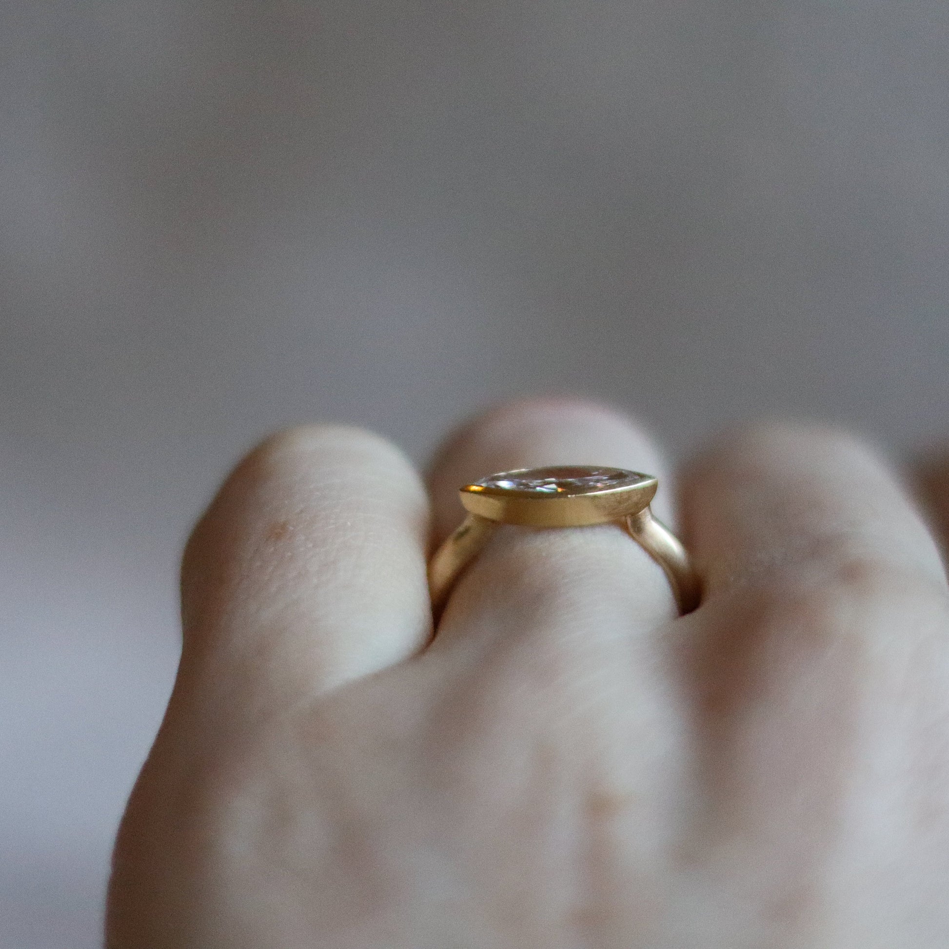 Elegant 18ct yellow gold ring set with a marquise-cut diamond in a minimalist bezel, worn on the finger