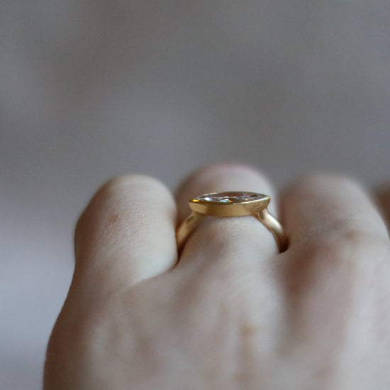 Elegant 18ct yellow gold ring set with a marquise-cut diamond in a minimalist bezel, worn on the finger