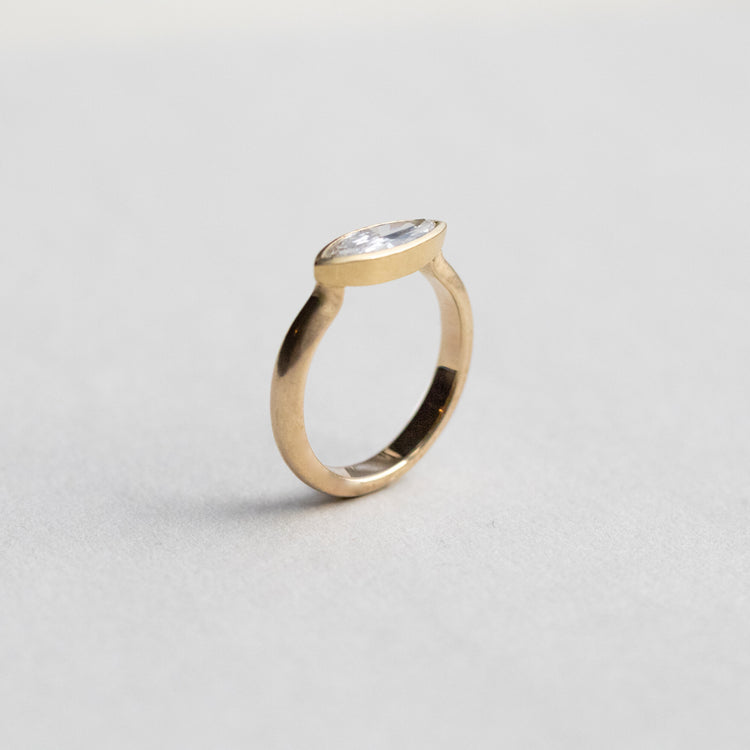 “Elegant 18ct yellow gold ring set with a marquise-cut diamond in a minimalist bezel, paper shot side view