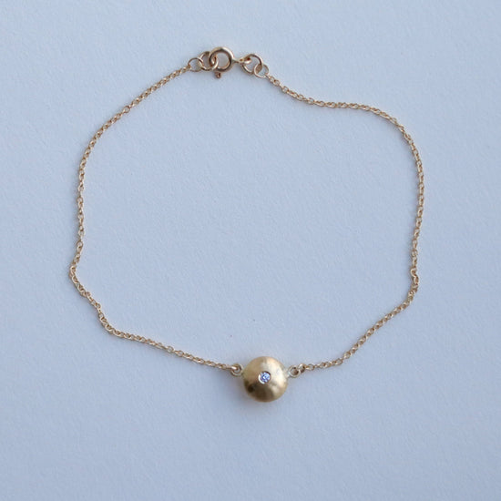 Minimalist 18ct yellow gold pendant necklace featuring a smooth rounded charm in-line on a fine gold chain singular diamond set  paper shot front
