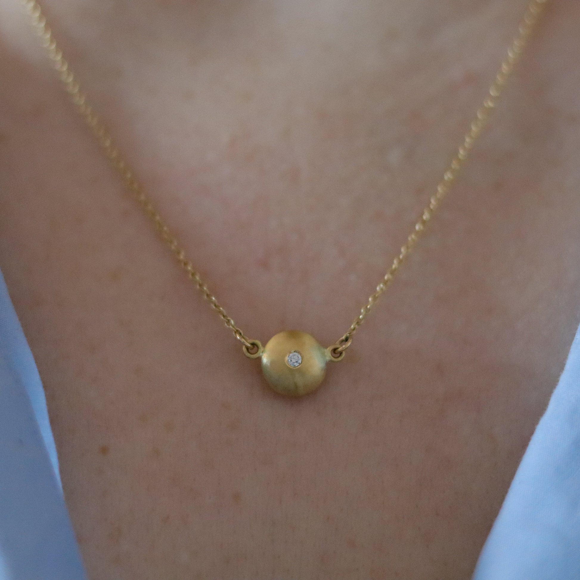 Minimalist 18ct yellow gold pendant necklace featuring a smooth rounded charm in-line on a fine gold chain singular diamond set  - model