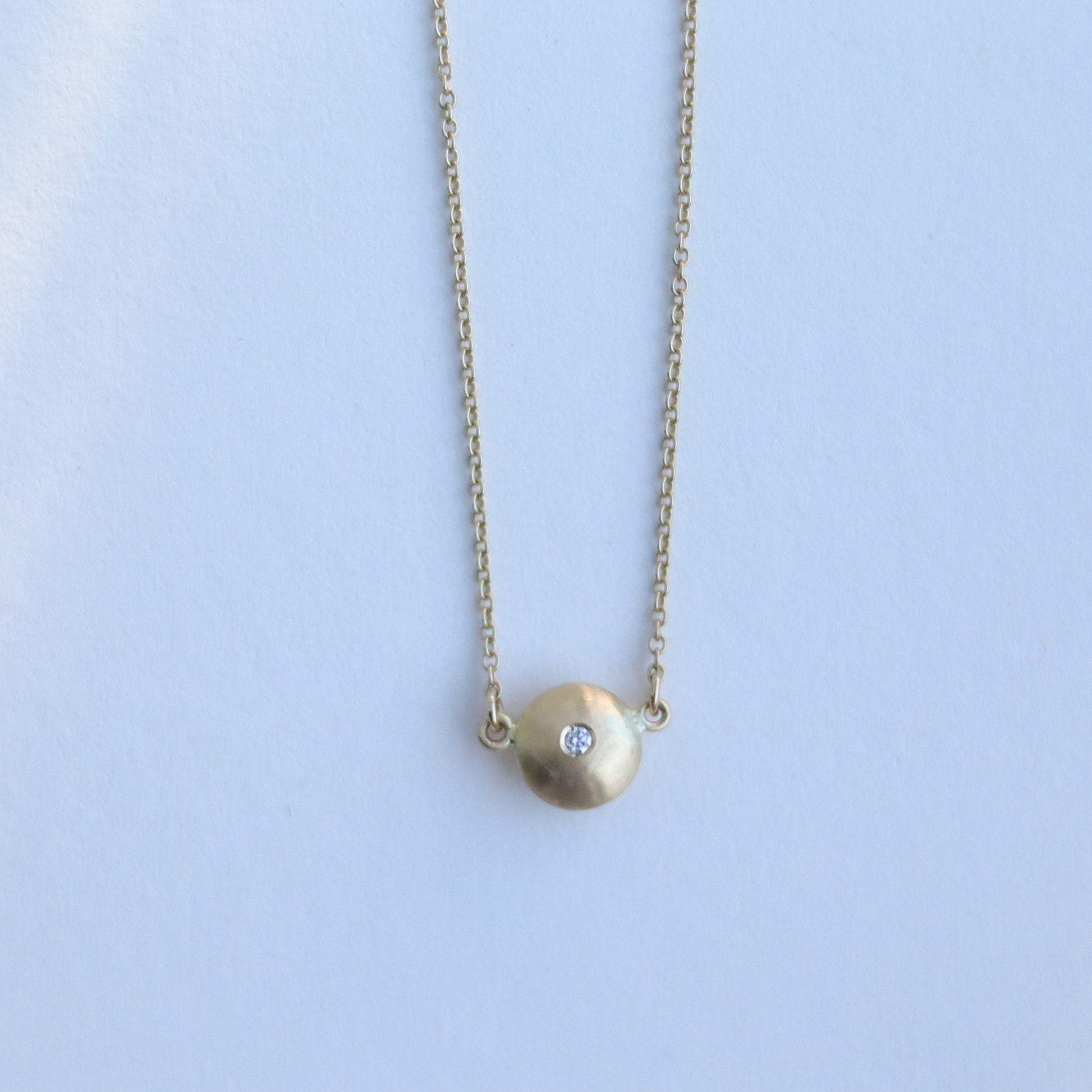 Minimalist 18ct yellow gold pendant necklace featuring a smooth rounded charm in-line on a fine gold chain singular diamond set  paper shot