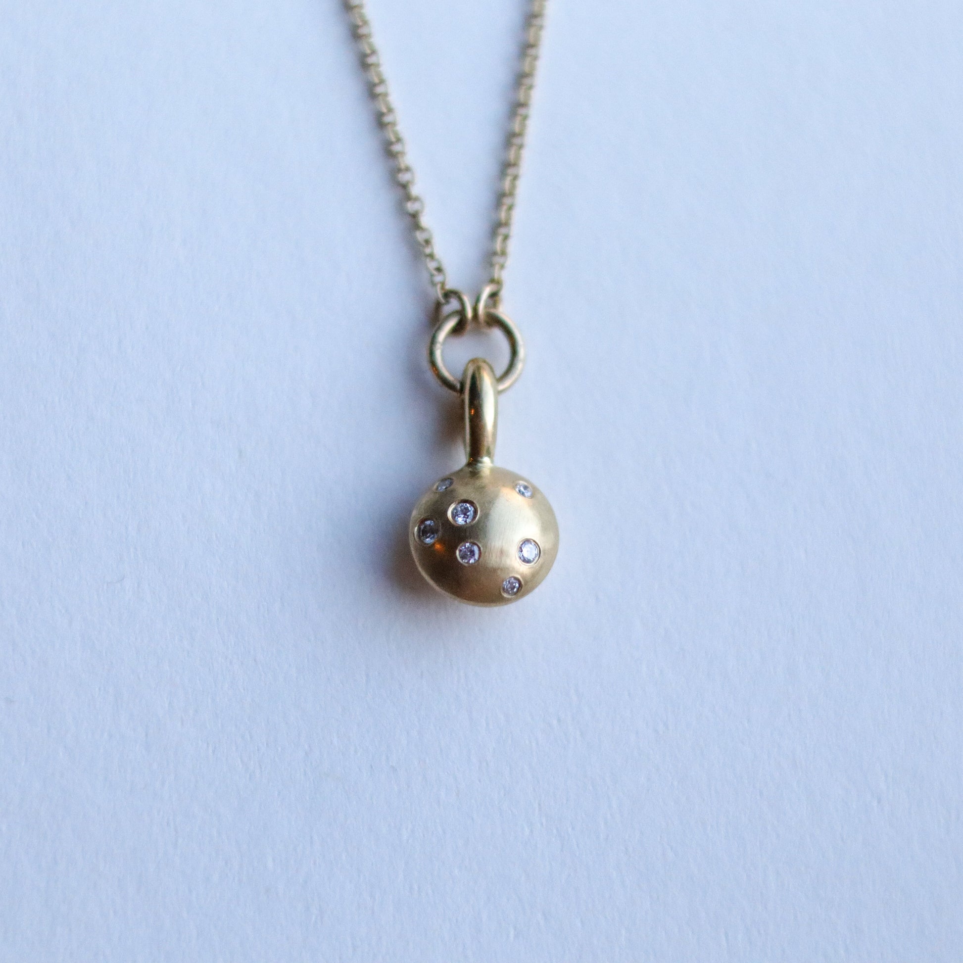 Minimalist solid 18ct yellow gold necklace featuring a brushed gold spherical pendant set with scattered diamonds looped onto a fine solid gold chain