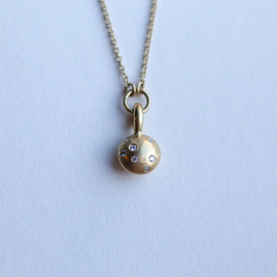 Minimalist solid 18ct yellow gold necklace featuring a brushed gold spherical pendant set with scattered diamonds looped onto a fine solid gold chain