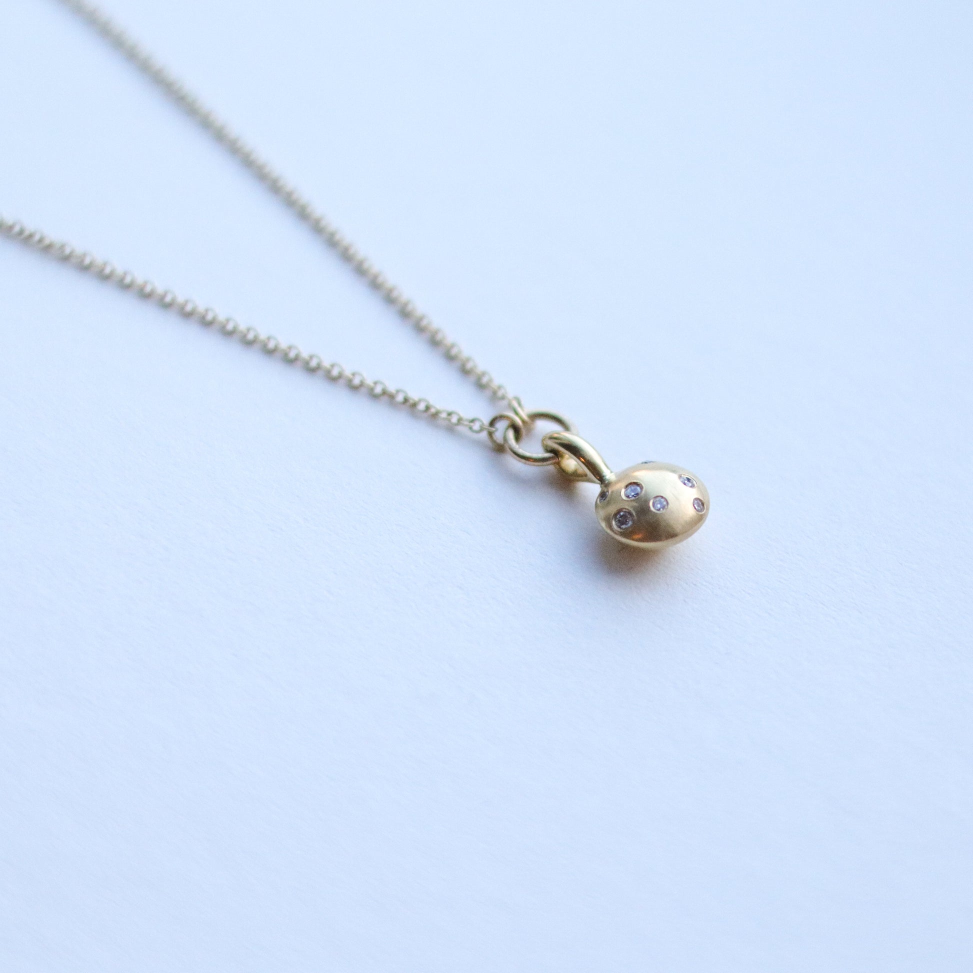 Minimalist solid 18ct yellow gold necklace featuring a brushed gold spherical pendant set with scattered diamonds looped onto a fine solid gold chain