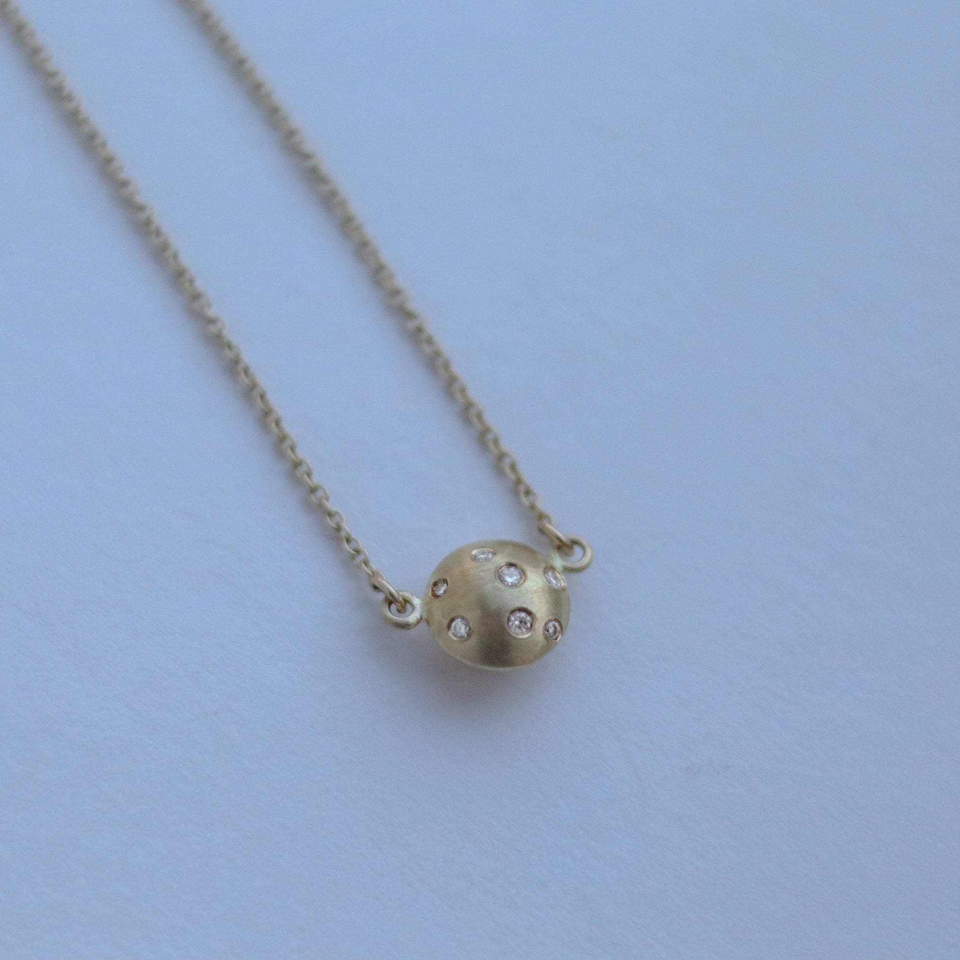 goldfinch jewellery Minimalist solid 18ct yellow gold necklace featuring a brushed gold spherical pendant set with scattered diamonds in-line on a solid gold fine chain