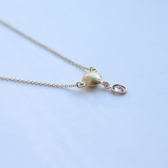 Luxury gold sphere pendant necklace set with diamonds, suspended from a delicate gold chain. shot of back