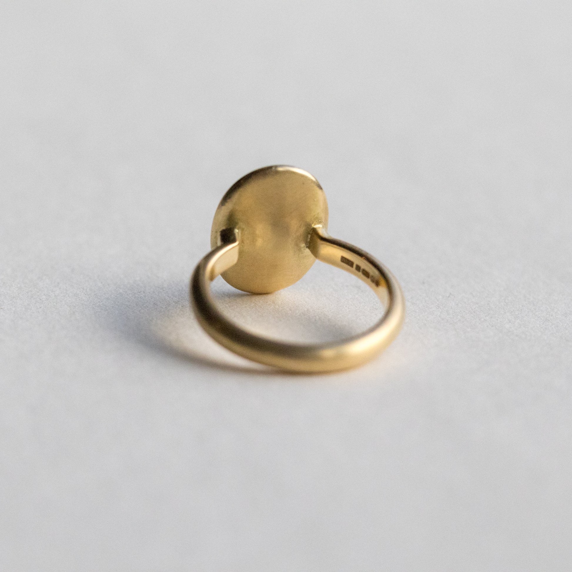 Contemporary 18ct yellow gold oval disc ring with scattered diamond detailing, back is shown on paper