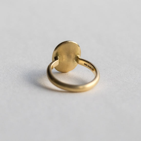 Contemporary 18ct yellow gold oval disc ring with scattered diamond detailing, back is shown on paper