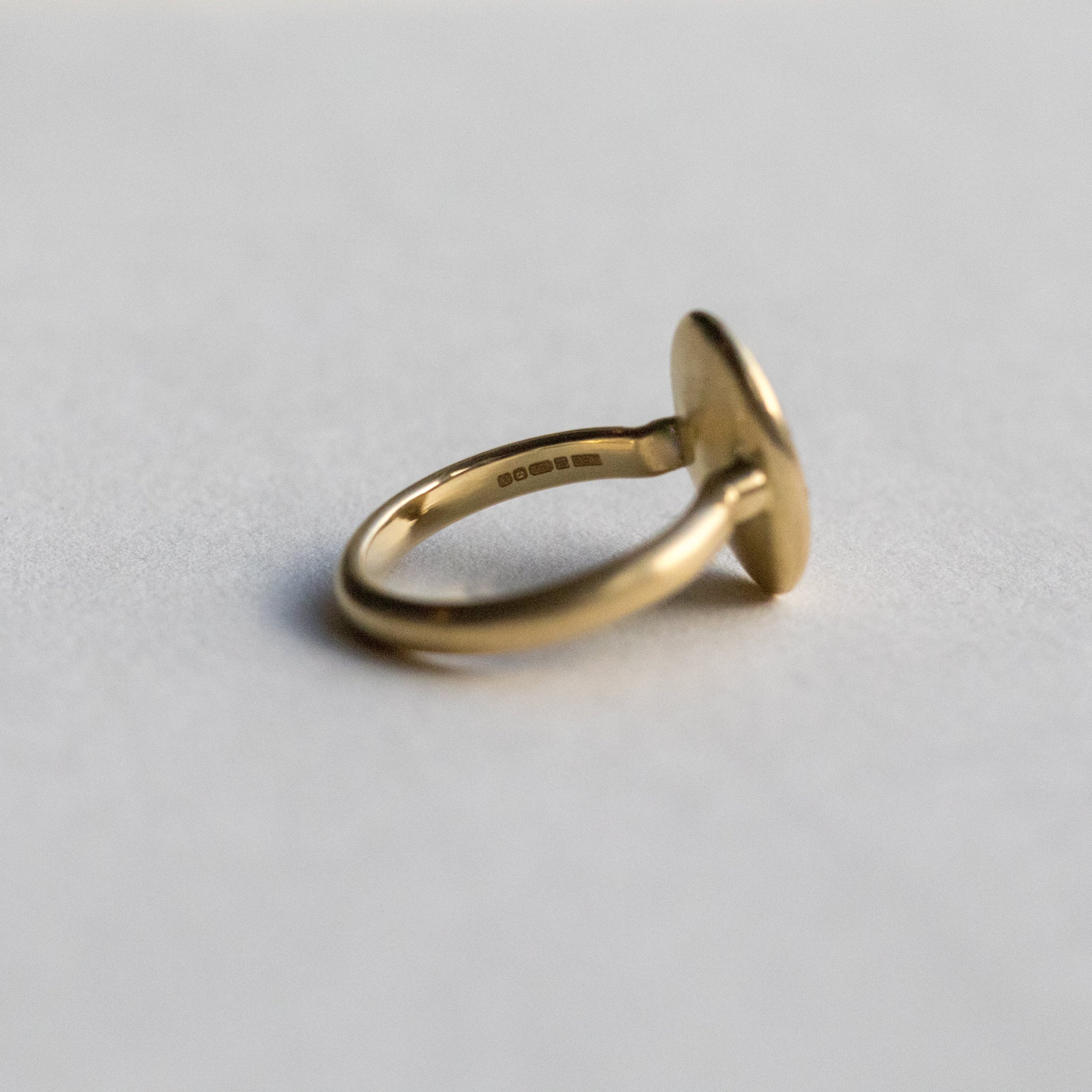 Contemporary 18ct yellow gold oval disc ring with scattered diamond detailing, inside shown on paper