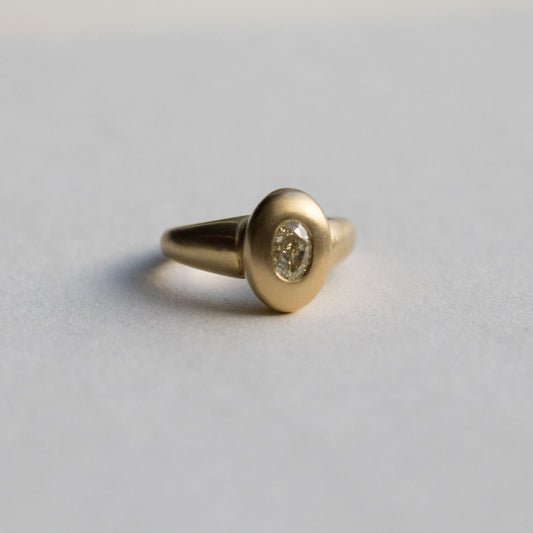 solid heavy 18ct yellow gold curved oval signet ring with oval natural yellow diamond with brushed gold. photographed on paper front view 