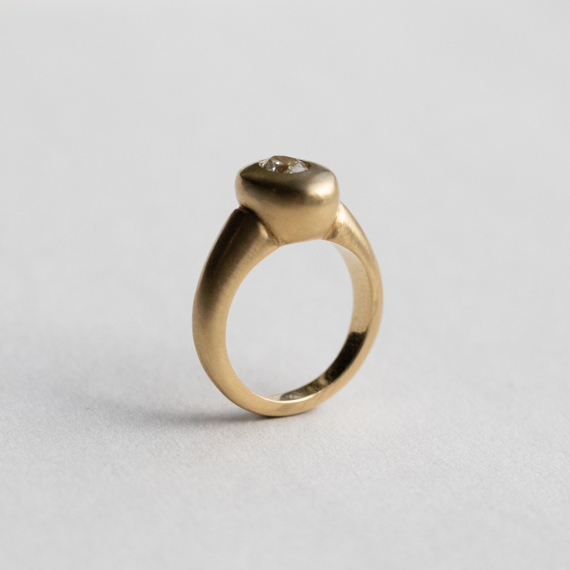 solid heavy 18ct yellow gold curved oval signet ring with oval natural yellow diamond with brushed gold. photographed  on paper at side angle
