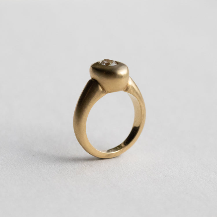 solid heavy 18ct yellow gold curved oval signet ring with oval natural yellow diamond with brushed gold. photographed  on paper at side angle